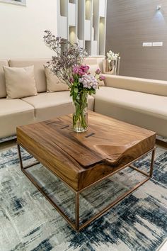 a living room with couches, tables and flowers in vases on the coffee table