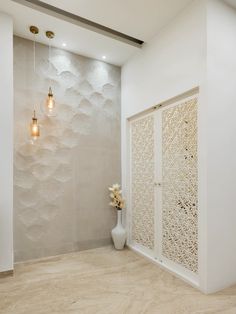a white vase with flowers in it sitting next to a wall mounted shower head and light fixture