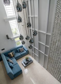 a living room filled with blue couches next to a tall white wall and windows