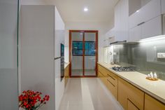 a kitchen with white counter tops and wooden cabinets next to a vase filled with red flowers