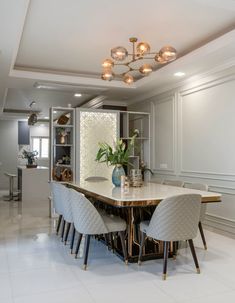 a dining room table with four chairs and a vase on the center island in front of it